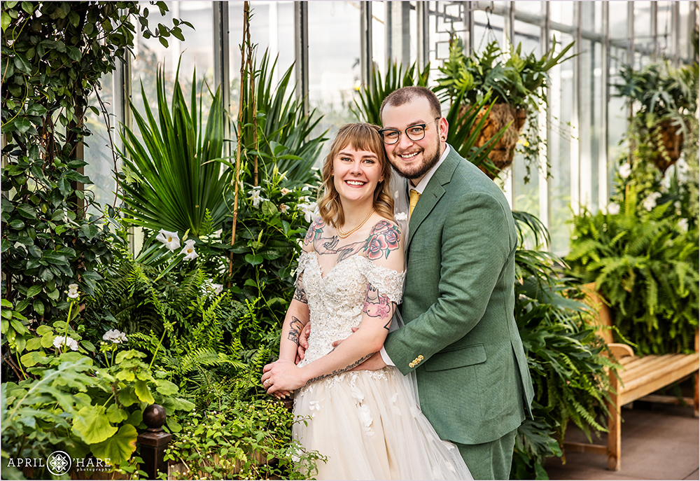 Wedding couple pose for a photo with the tropical plants at the Orangery greenhouse at Denver Botanic Gardens