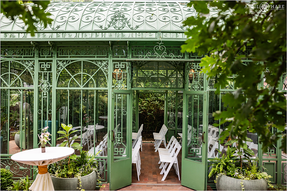 View of the Woodland Mosaic Solarium set up for a wedding ceremony from the outside of the greenhouse at Denver Botanic Gardens