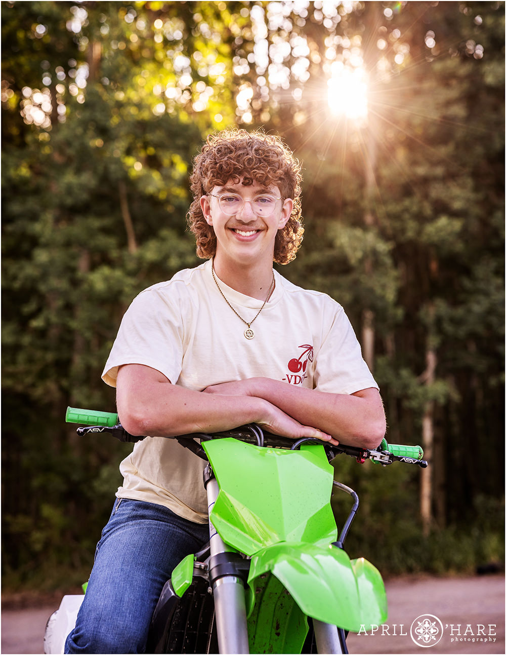 Teenaged boy poses for a photo with his dirtbike at a trailhead in Colorado