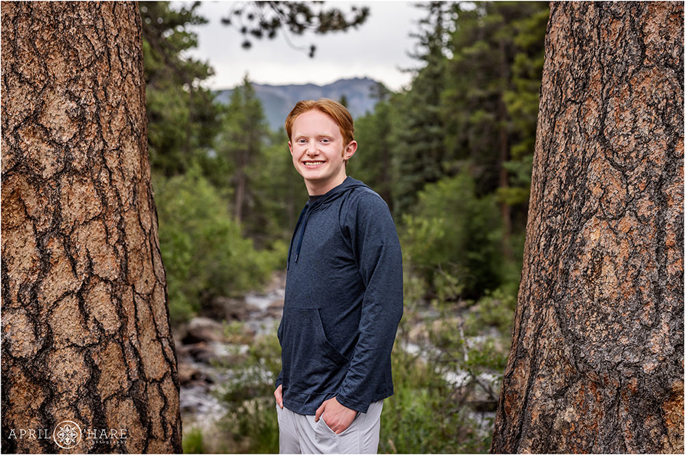 Senior boy stands in front of Big Thompson River at Rocky Mountain National Park in Colorado