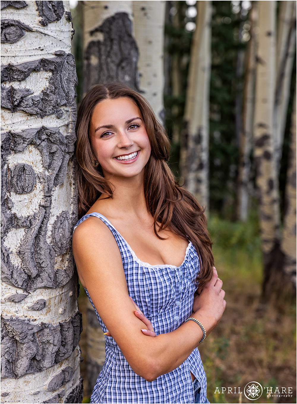 High school senior leans against an aspen tree in a Colorado mountain meadow