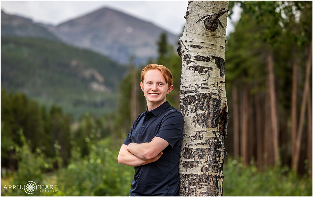 Senior boy leans against an aspen tree at Rocky Mountain National Park in Colorado