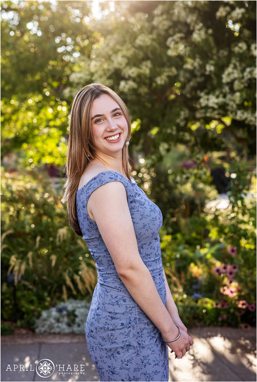 Sunshine peeks through the flowering tree in the backdrop for a senior photo at Denver Botanic Gardens