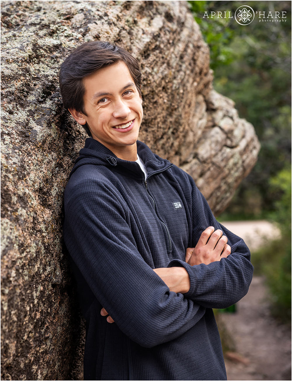 High school senior boy leans against a rock for his senior photo at Castlewood Canyon State Park