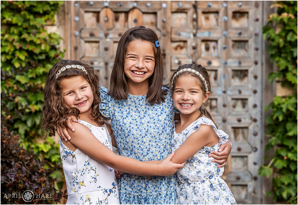 Cute photo of three sisters hugging in the Oval Garden at Denver Botanic gardens in Colorado
