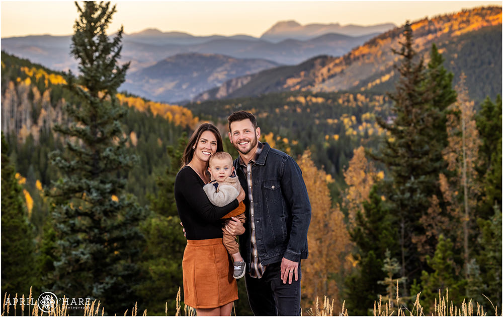 Colorado mountain backdrop dotted with golden aspen trees for a family portrait for a family of three with a baby boy