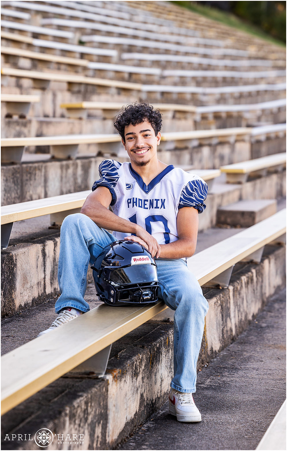 Senior Photo of a young man sitting in the stands wearing his uniform at Boulder High School