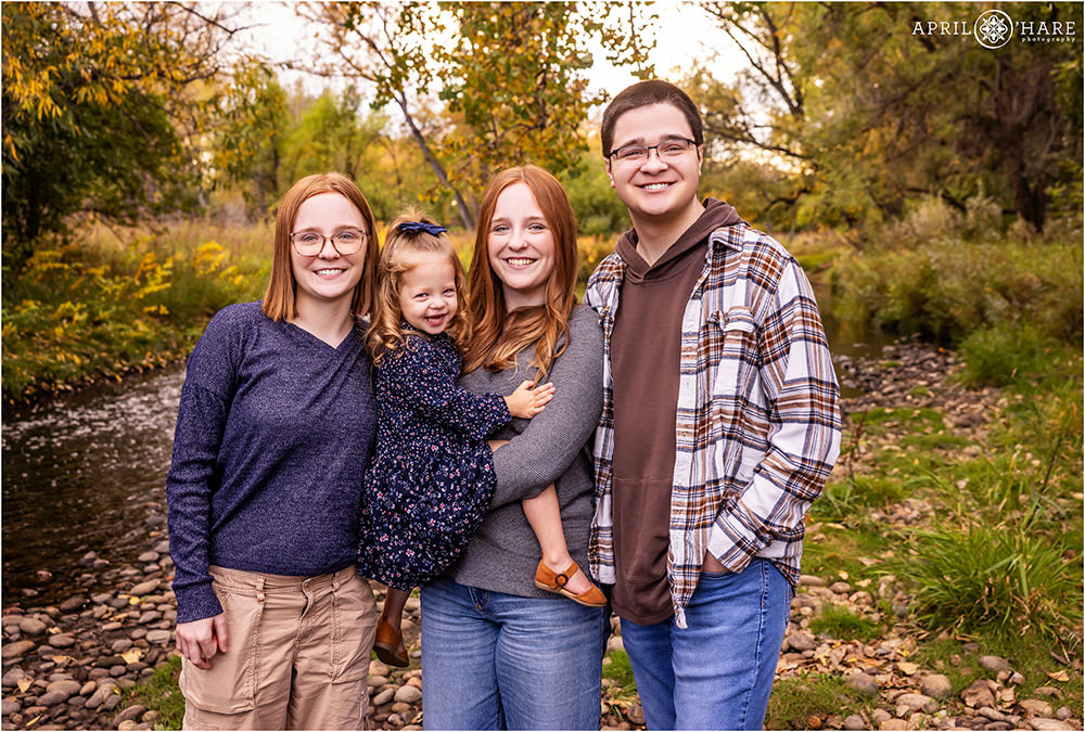 Four siblings pose for a cute photo together next to Clear Creek in Wheat Ridge Colorado