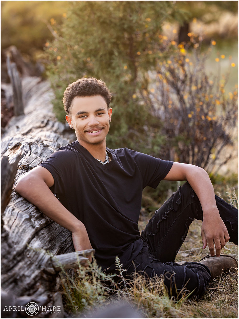 High school senior leans against a large fallen log at his senior photoshoot at West Mount Falcon