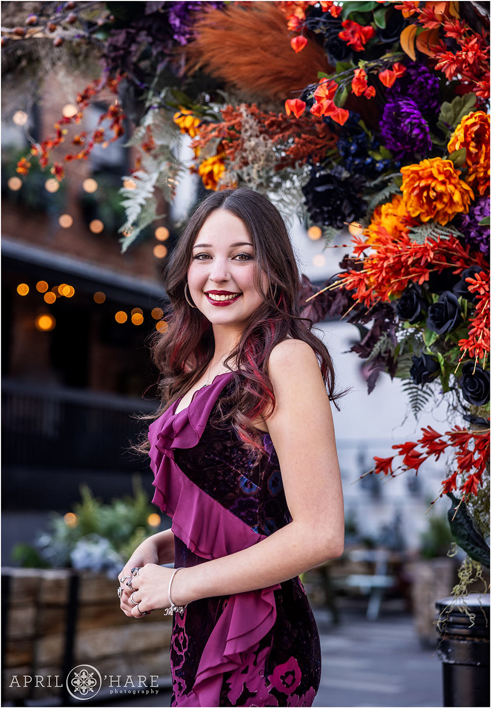 Beautiful purple and orange flower backdrop for a senior girl photoshoot in downtown Denver at Dairy Block