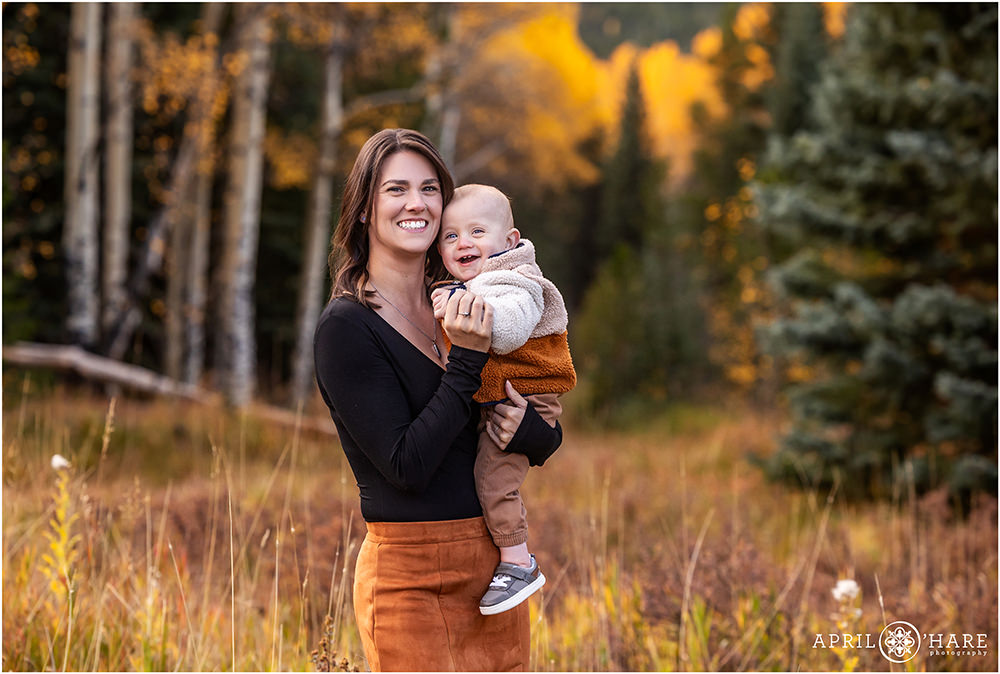 Sweet photo of a baby boy smiling with his mama in a pretty mountain meadow with golden aspens during fall