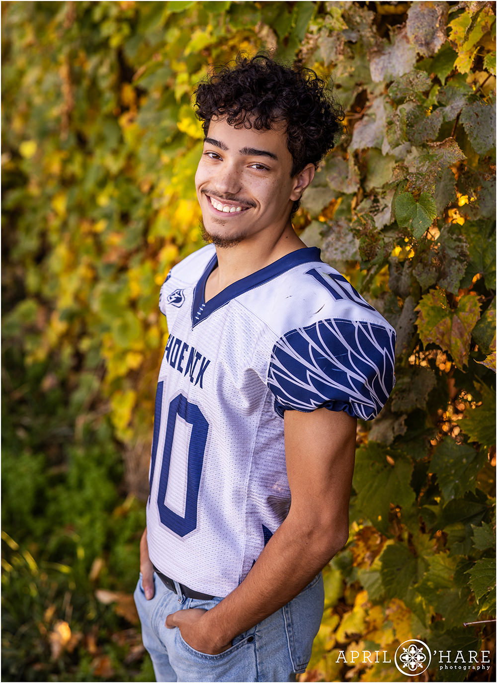 High school senior football player poses in the fall color wearing his football jersey at Boulder High School