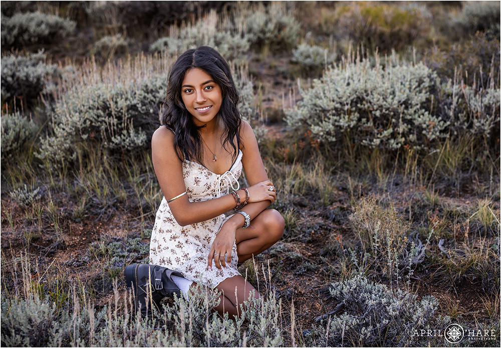 Senior girl in the pretty blue green bushes at RMNP for her Senior Portrait Session in Colorado