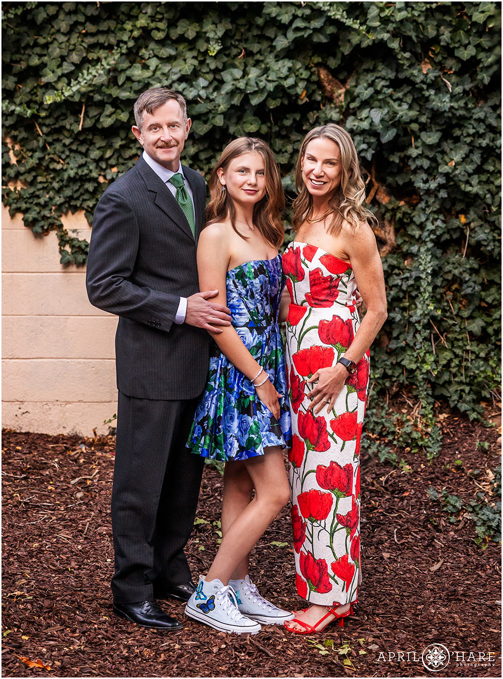 Bat Mitzvah girl with her parents posing for a portrait in front of the Ivy Wall at Rembrandt Yard in Boulder CO