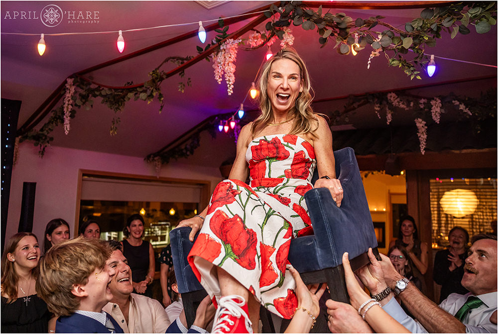 Mom is lifted up in the chair during horah dance at her daughter's bat mitzvah party at Rembrandt yard in Boulder CO