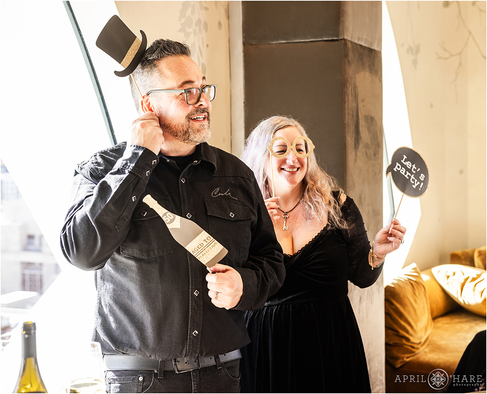 Couple hold up photobooth signs at a 50th birthday party brunch at Stellar Jay at the Populous Hotel in Denver CO