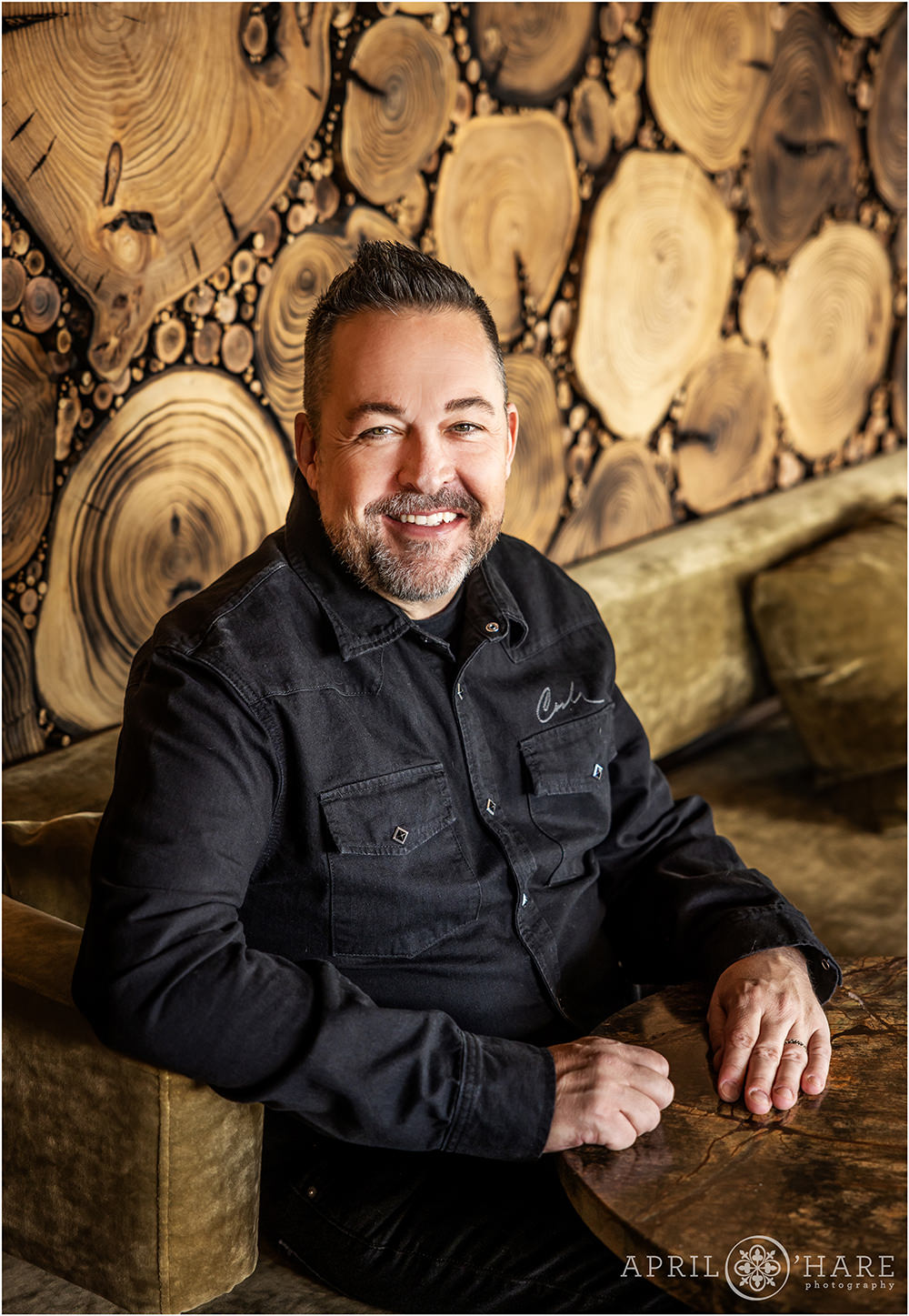 Nice portrait of a man on his birthday in front of the wood wall at Stellar Jays Rooftop Bar in Denver CO