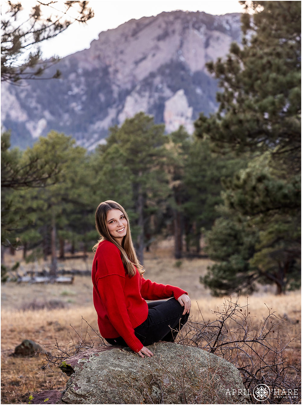 A girl in a red sweater poses for a portrait at her family photoshoot in South Boulder Colorado