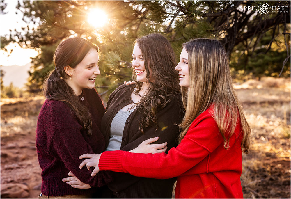 Three young adult sisters laugh together at their family photoshoot in Boulder CO