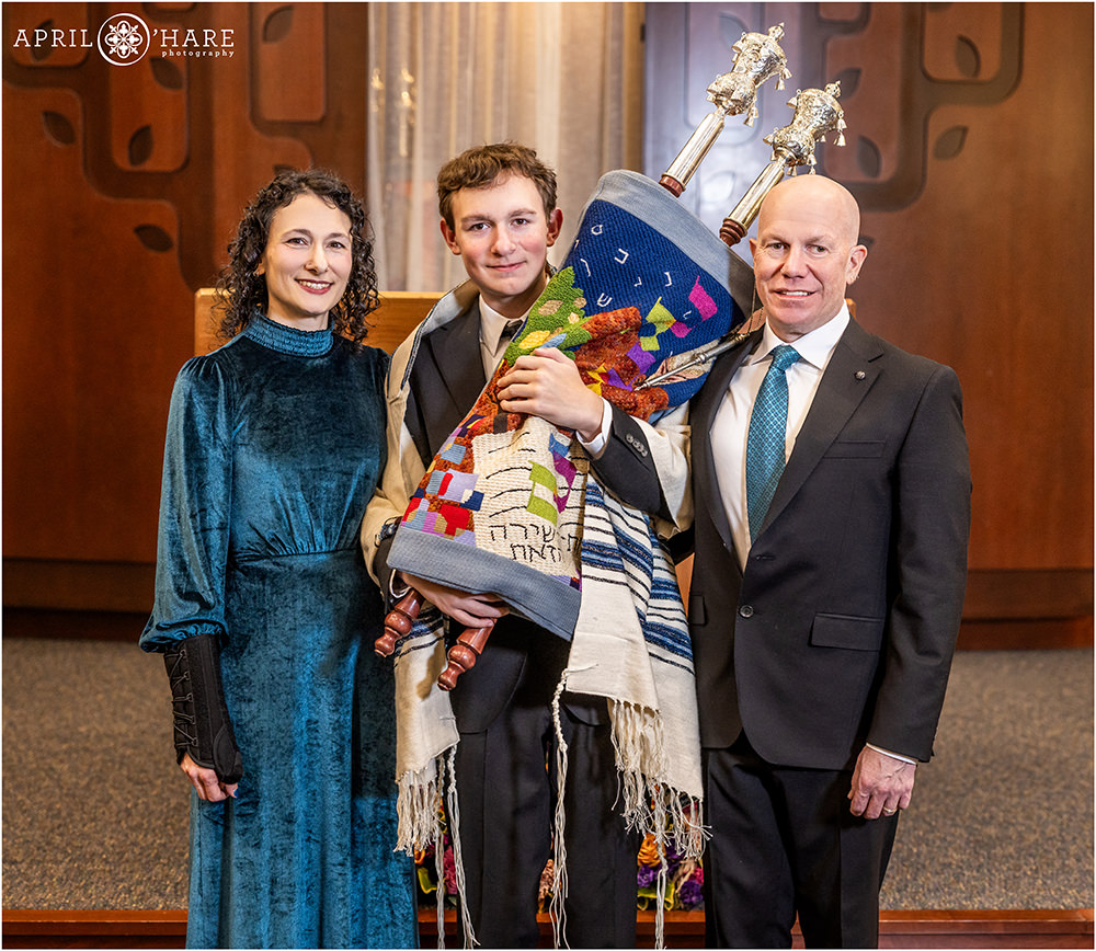 Bar mitzvah boy holds the Torah with his parents at his side on the day of his bar mitzvah rehearsal at Temple Sinai in Denver Colorado