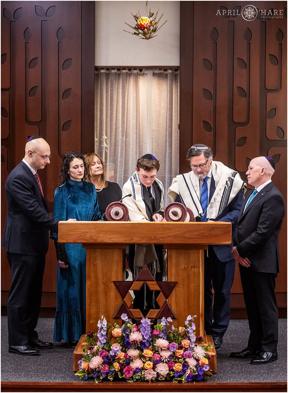 Bar mitzvah boy surrounded by his rabbi and family as he reads from the Torah at his bar mitzvah rehearsal at Temple Sinai in Denver CO