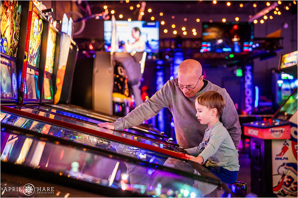 A father shows his young son how to play pinball at Super Awesome Fun Factory in Denver CO