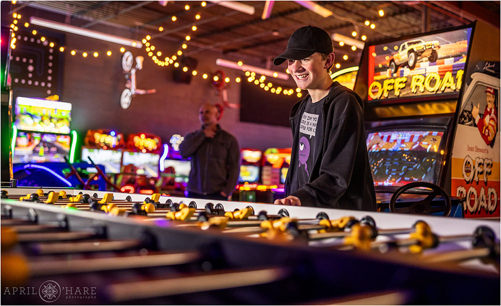 A young man plays foosball at his bar mitzvah party at Super Awesome Fun Factory in Denver CO