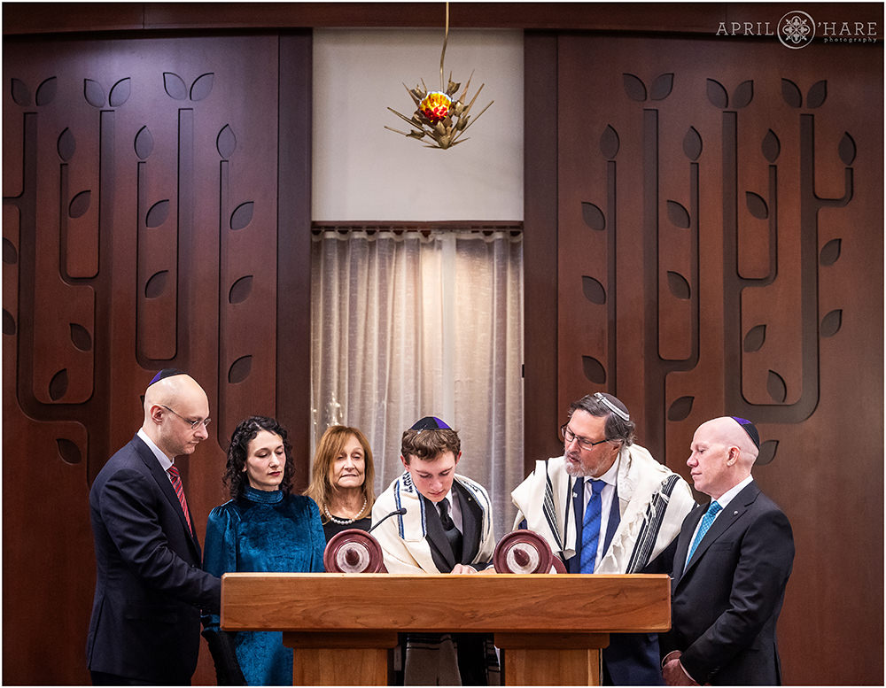 A young man reads from the Torah with his family at his side in Denver CO