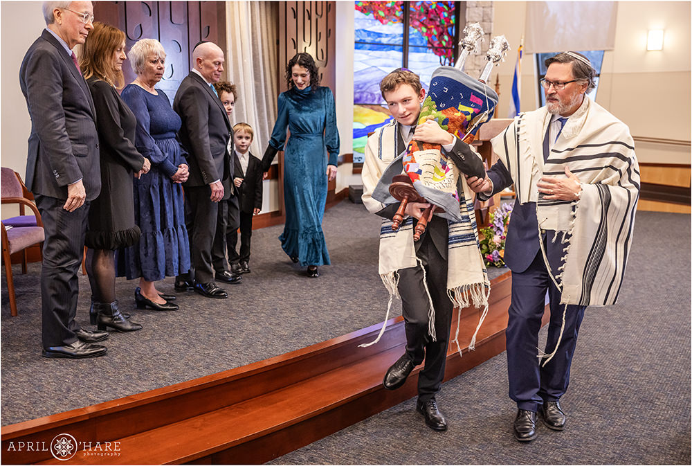 A young man carries the Torah around the congregation at Temple Sinai in Denver, CO