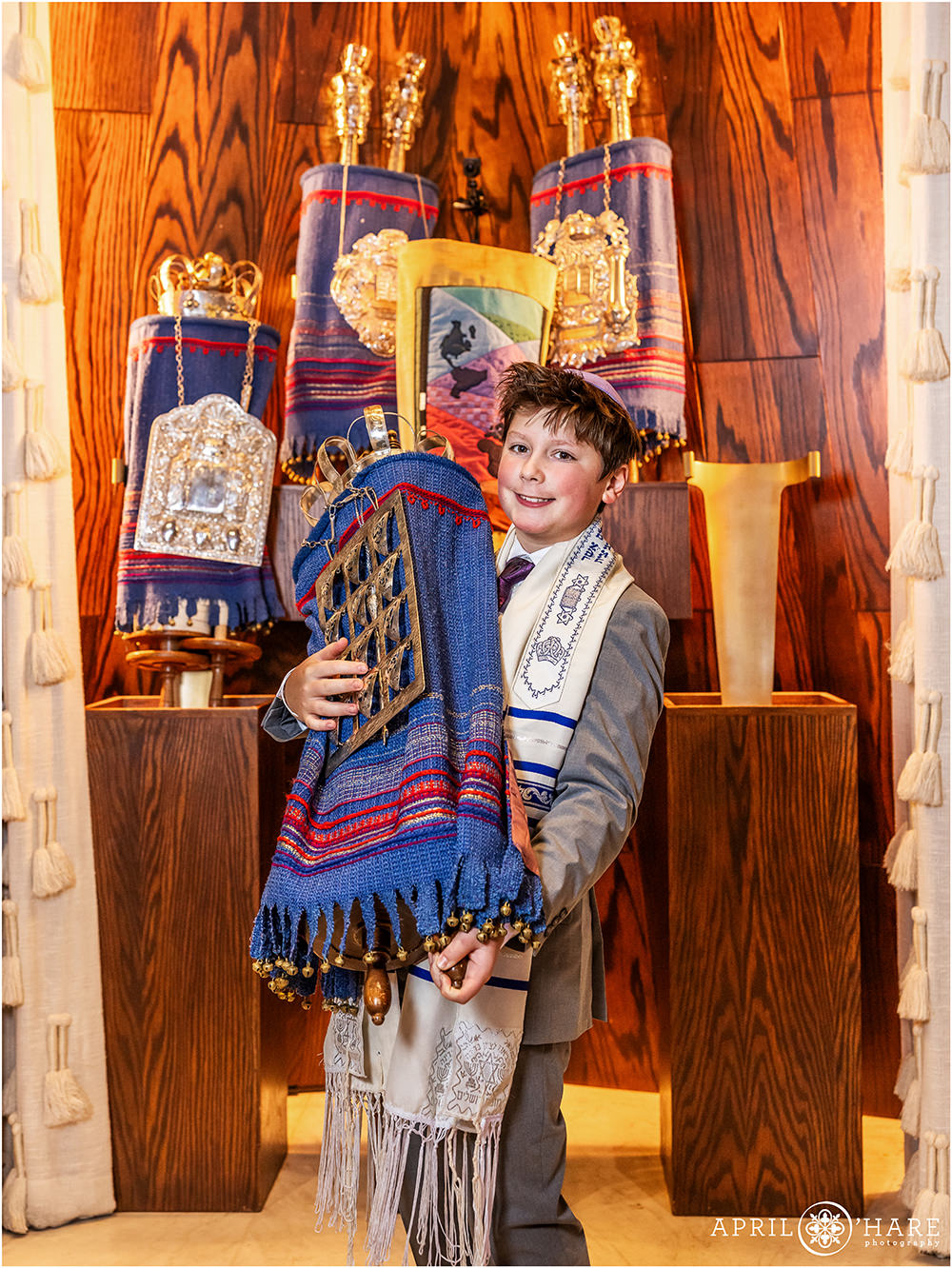 A young man holds the torah for a photo at Temple Emanuel at his bar mitzvah