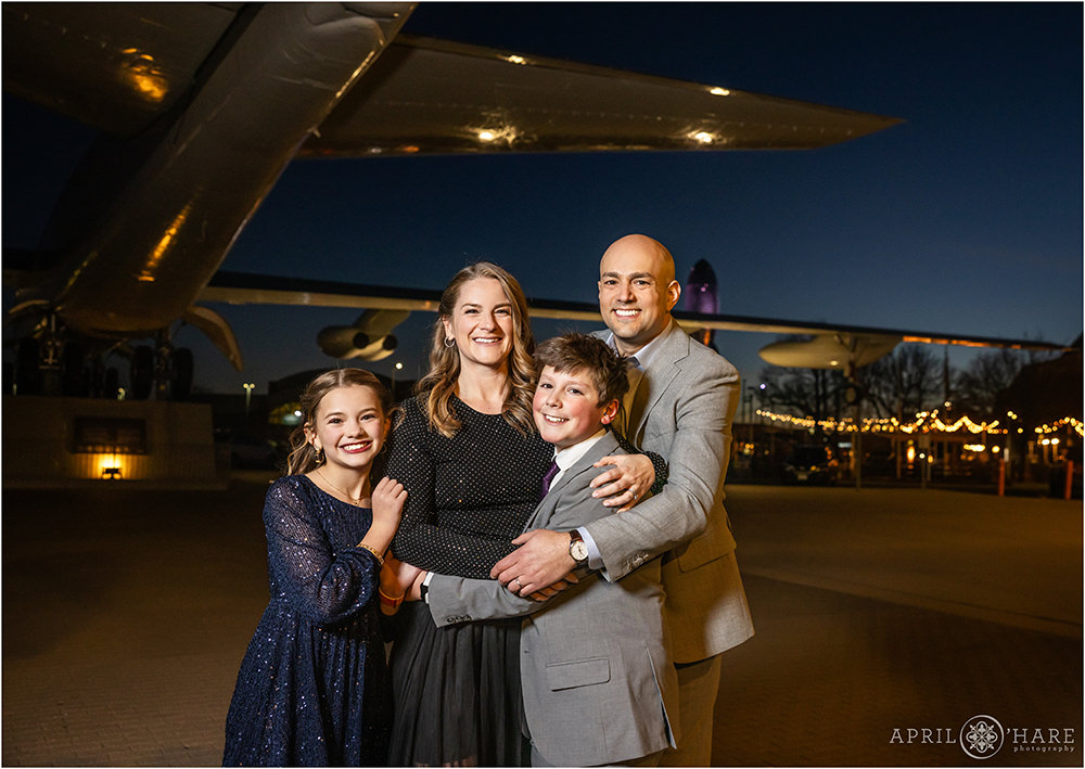 Cute family photo with a huge plane in the backdrop at their son's bar mitzvah party at Wings over the Rockies in Denver CO