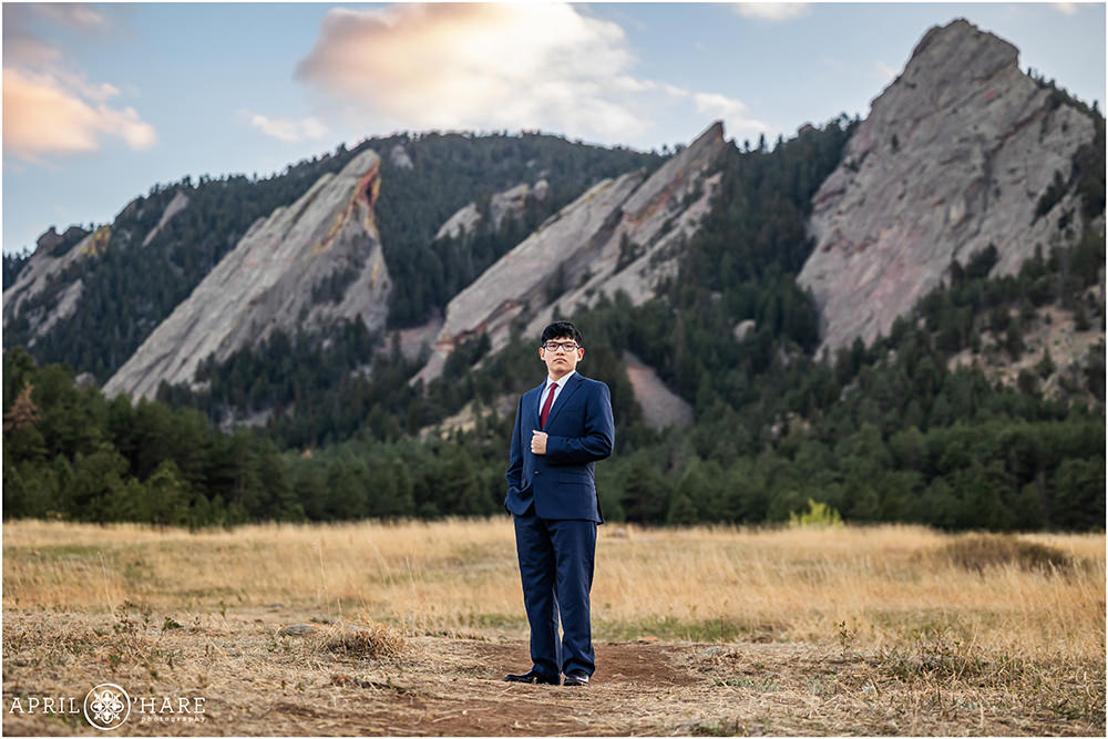 Serious pose for a college grad wearing a blue suit in front of the Flatirons on a spring day in Boulder CO