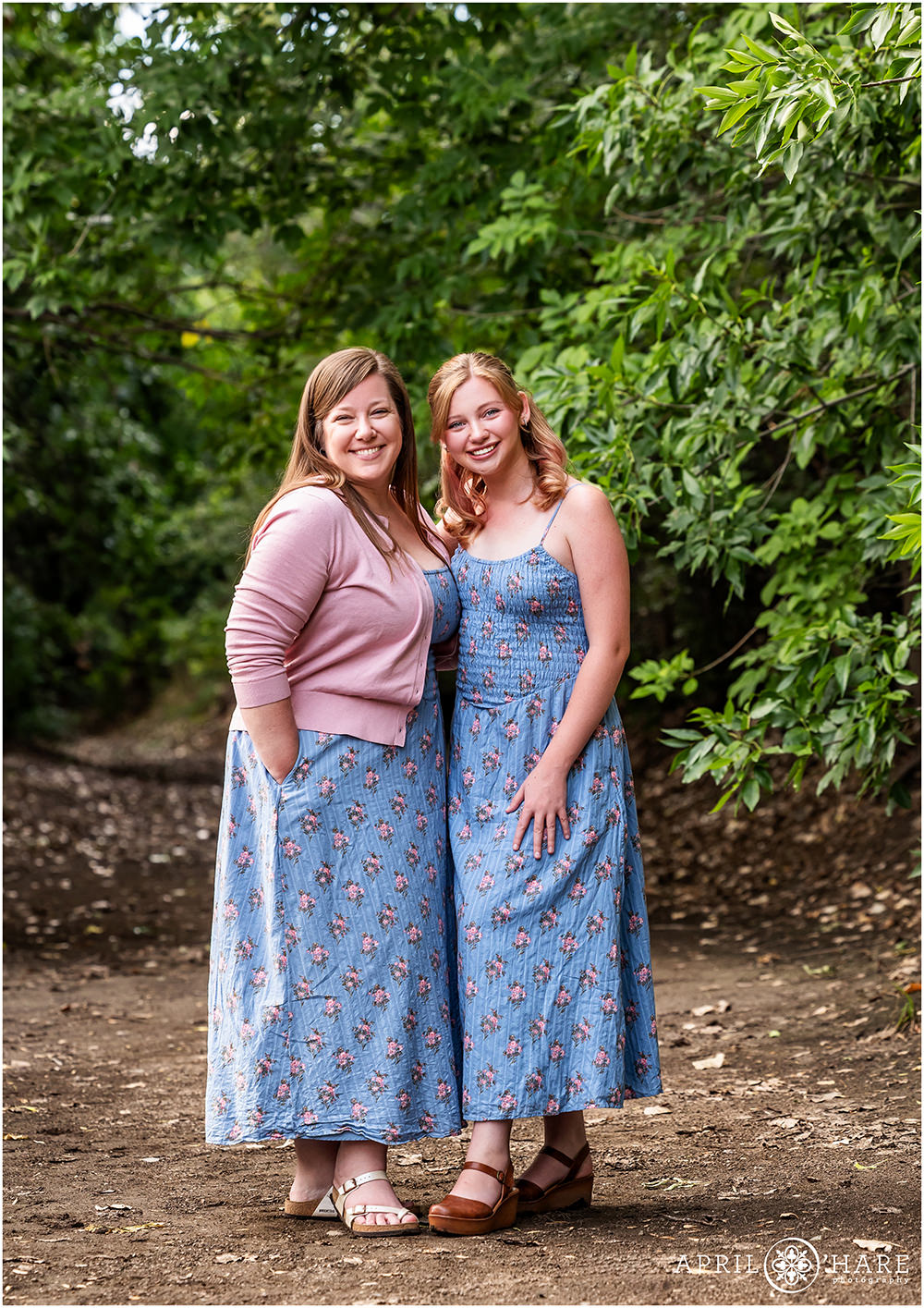 Family Photo of mom with her daughter in matching floral dresses in front of Tree Backdrop at Bible Park in Denver, CO